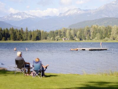 older couple sitting in lawn chairs staring at a lake